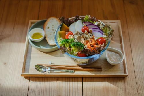 a bowl of salad on a wooden tray with chopsticks at Ten to Sen Guesthouse in Takamatsu