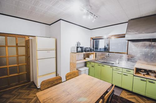 a kitchen with green cabinets and a wooden table at 【佐渡/一棟貸切】オーシャンビュー古民家SeaSideStory椿 離れ in Sado