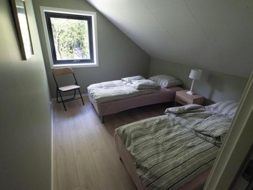 1 dormitorio con 2 camas, silla y ventana en Sjøhuset, en Løding