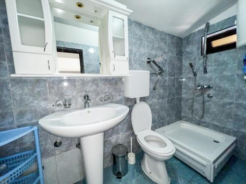 a bathroom with a sink and a toilet and a mirror at Hilja's Oliven Garden Bungalows in Ulcinj
