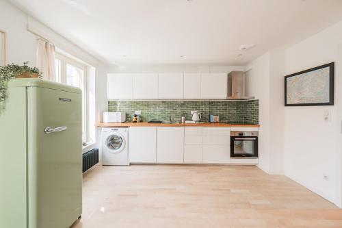 une cuisine avec des armoires blanches et un réfrigérateur vert dans l'établissement Le Strasbourgeois - Appt 60m² - 6 voyageurs, à Strasbourg