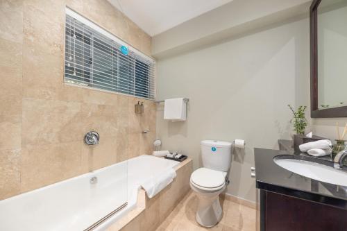 a bathroom with a tub and a toilet and a sink at O on Kloof Boutique Hotel & Spa in Cape Town