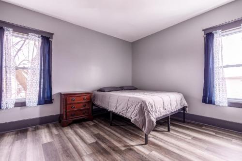 a bedroom with a bed and a dresser and two windows at Spacious 6BR 2Bath Close the Falls in Niagara Falls
