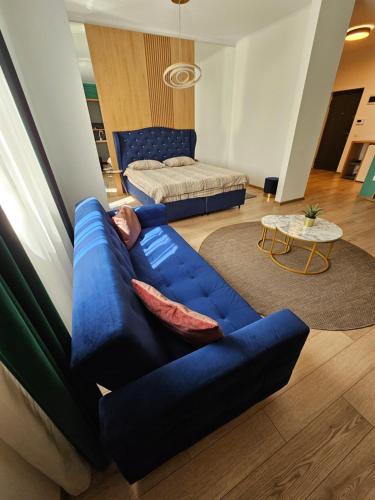 een woonkamer met een blauwe bank en een bed bij POT Apartments in Târgu-Mureş