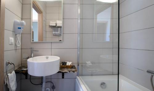 a white bathroom with a sink and a shower at 1951 Suites in Kalabaka