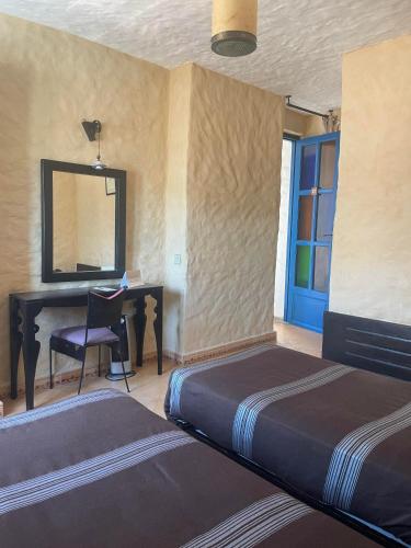 a bedroom with two beds and a desk and a mirror at Riad Al Madina in Essaouira