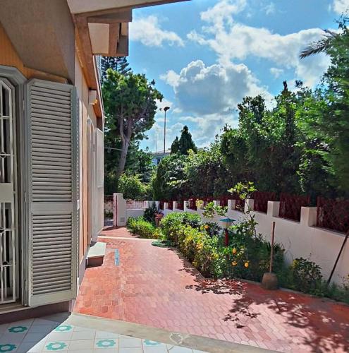 a brick walkway next to a building with a garden at Villetta indipendente a due passi dal mare in Fontane Bianche