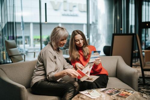 two women sitting on a couch looking at a book at Tallink City Hotel in Tallinn