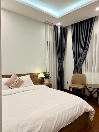 a bedroom with a white bed and a desk and curtains at SAFFRON Dalat in Da Lat