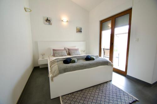 um quarto branco com uma cama e uma janela em Apartmani Rajković em Matulji