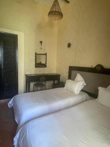 a bedroom with two beds and a desk in it at Riad Al Madina in Essaouira