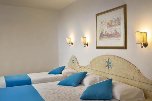 two beds in a hotel room with blue pillows at Hotel Villa Campana in Cala Liberotto