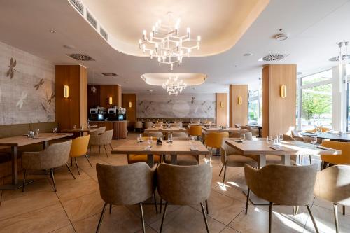a restaurant with wooden tables and chairs and a chandelier at Hotel Marina Port in Balatonkenese