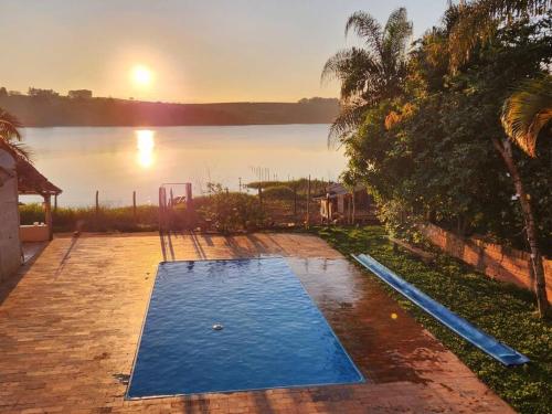 an empty swimming pool in front of a lake at Casa Alfenas Represa Furnas c/ Piscina Aquecida 12 pessoas in Alfenas