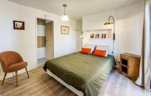 a bedroom with a bed with orange pillows and a chair at 4 Bedroom Amazing Home In Plouézec in Plouézec