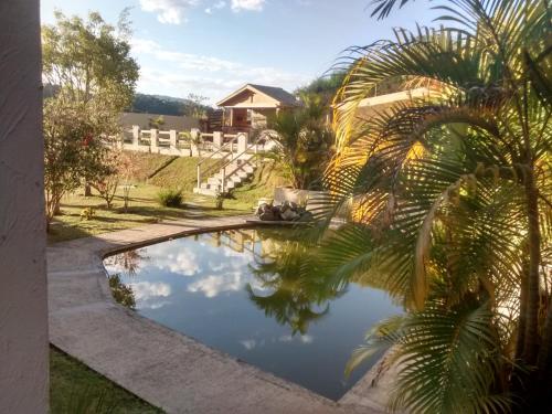 einem Pool mit Palmen und einem Haus in der Unterkunft Chacara Toca do urso in Santa Isabel