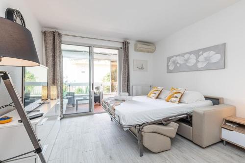 ein weißes Schlafzimmer mit einem Bett und einem Balkon in der Unterkunft Beau studio avec terrasse ensoleillée - Proche mer in Cagnes-sur-Mer