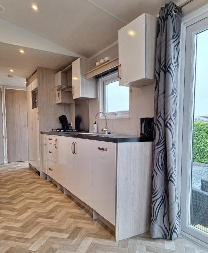 a kitchen with white cabinets and a large window at Beach Resort Nieuwvliet Bad - NV 37 in Nieuwvliet
