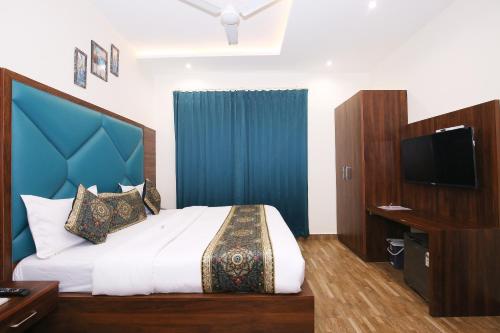 a bedroom with a bed with a blue headboard and a television at Hotel East Wood Amritsar in Amritsar