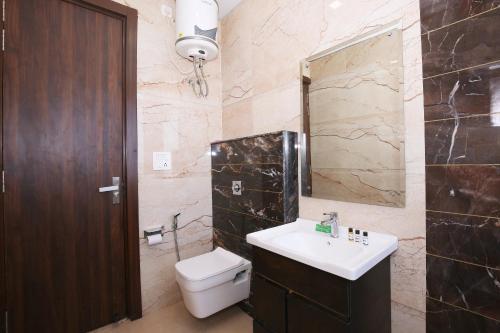 a bathroom with a sink and a toilet and a mirror at Hotel East Wood Amritsar in Amritsar