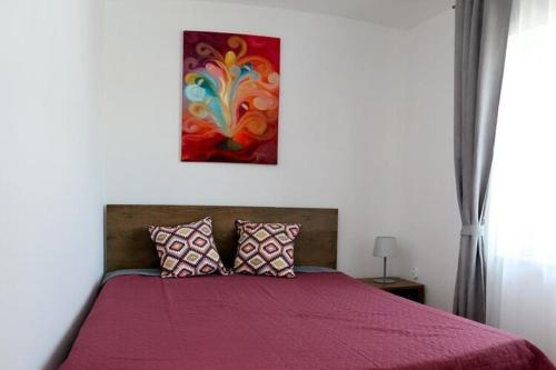 Un dormitorio con una cama roja con una pintura encima. en Cottage, 2 bedrooms, swimming pool, Grzybowo en Grzybowo