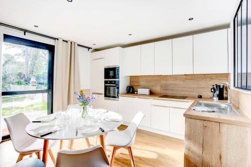 une cuisine avec des armoires blanches et une table et des chaises dans l'établissement Sarah 3 - Appt à avec jardin à 200 m de la plage, à Fréhel