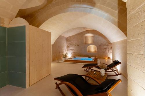 a room with a bathtub and chairs in a building at Endea Suite Rooms & Lounge SPA in Matera