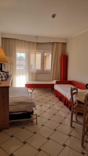 a bedroom with two beds and a table and a window at SUITE 225 Golf H PROMO SERVICE SRL in Castiglione della Pescaia