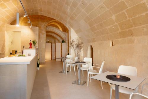 a restaurant with tables and white chairs and a brick wall at Endea Suite Rooms & Lounge SPA in Matera