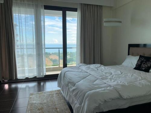 a bedroom with a large bed and a large window at Kitengule Apartment 002 in Dar es Salaam