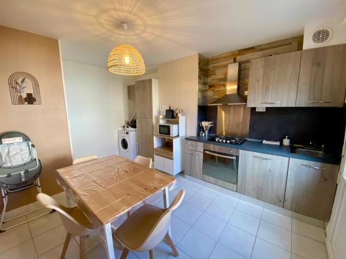 Il comprend une cuisine avec une table et des chaises en bois. dans l'établissement Les Dunes, à Le Portel