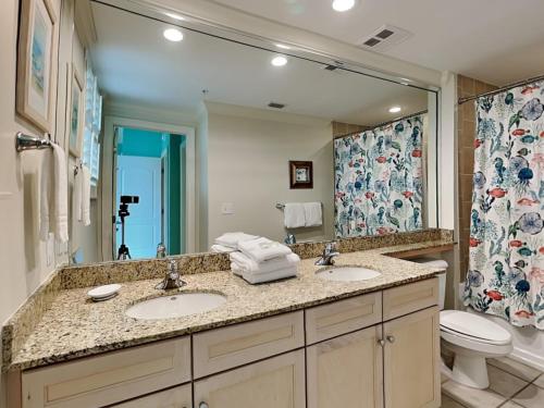 a bathroom with two sinks and a toilet and a mirror at Indigo East 1203 in Perdido Key
