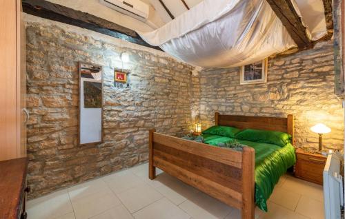a bedroom with a green bed and a stone wall at Gorgeous Home In Benkovac in Benkovac