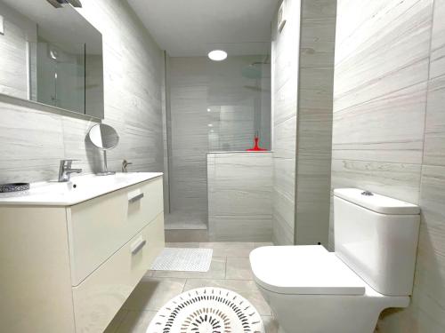 a white bathroom with a toilet and a sink at Castillo de Moraira in Moraira