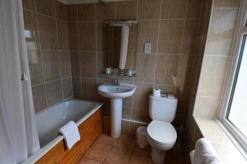a bathroom with a toilet and a sink and a tub at The Trouville Bournemouth in Bournemouth