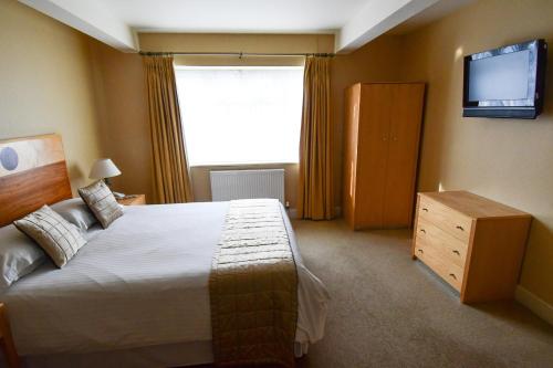 a bedroom with a large bed and a television at The Trouville Bournemouth in Bournemouth