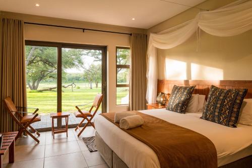a bedroom with a large bed and a large window at Hwange Safari Lodge in Dete