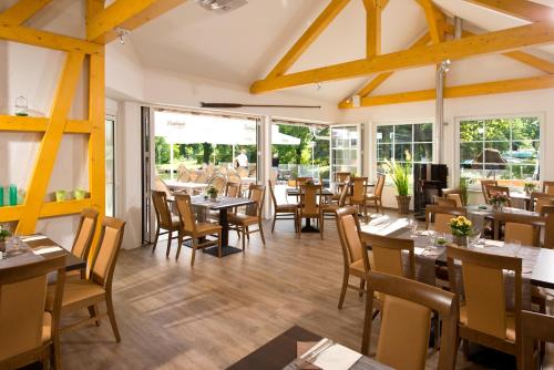 a restaurant with wooden tables and chairs and windows at Spreewaldhotel Stephanshof in Lübben