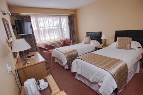 a hotel room with two beds and a television at The Trouville Bournemouth in Bournemouth