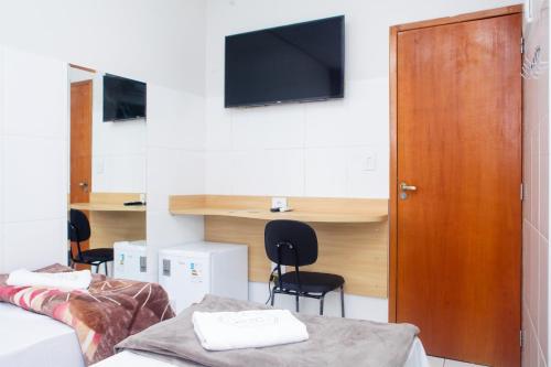 a room with two beds and a desk and a tv at Hotel New House in Sao Paulo