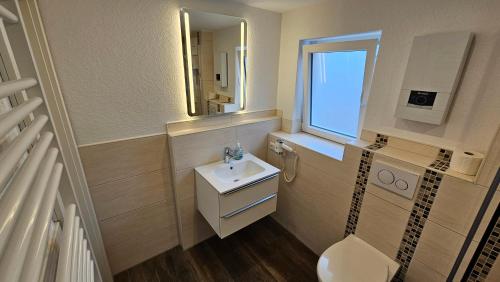 uma casa de banho com um lavatório, um WC e uma janela. em Hotel Dorfkrug Büsum - günstige Altbauzimmer Am Oland em Büsum