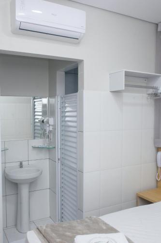 a white bathroom with a sink and a mirror at Hotel New House in Sao Paulo