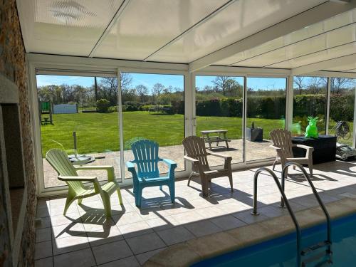 a screened in porch with chairs and a pool at Gîte Rosalie, piscine couverte chauffée - Au bord de l'eau Conciergerie in Plouagat