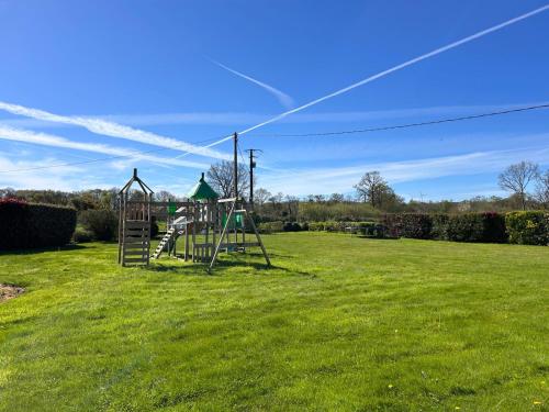 an empty playground in a grassy field at Gîte Rosalie, piscine couverte chauffée - Au bord de l'eau Conciergerie in Plouagat