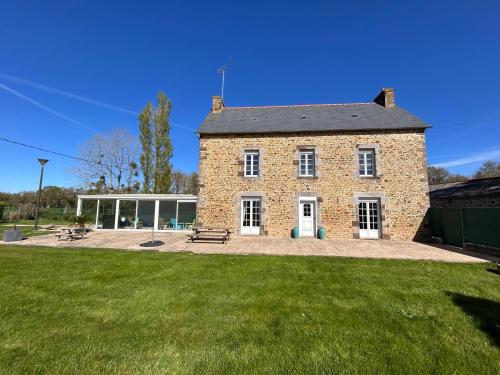 a large brick building with a grass yard at Gîte Rosalie, piscine couverte chauffée - Au bord de l'eau Conciergerie in Plouagat