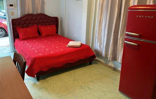 - une petite chambre avec un lit rouge et un réfrigérateur dans l'établissement Private Studio near Beach and Restaurants with AC, Unit 3, à San Juan