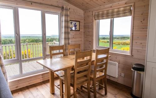 a dining room with a table and chairs and windows at Burgie Woodland Lodges in Forres