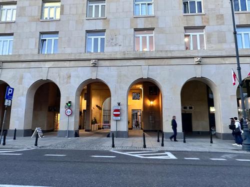 a large stone building with arches on a city street at Bez Kantów Art Rooms in Warsaw