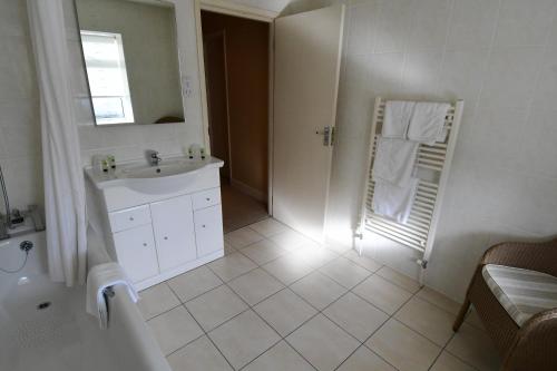 a white bathroom with a sink and a shower at The Trouville Bournemouth in Bournemouth