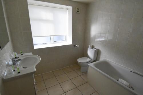 a bathroom with a sink and a tub and a toilet at The Trouville Bournemouth in Bournemouth